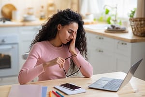 Brunette woman experiencing eye fatigue whilst working on her computer