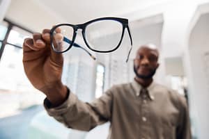 A man holding up a pair of glasses